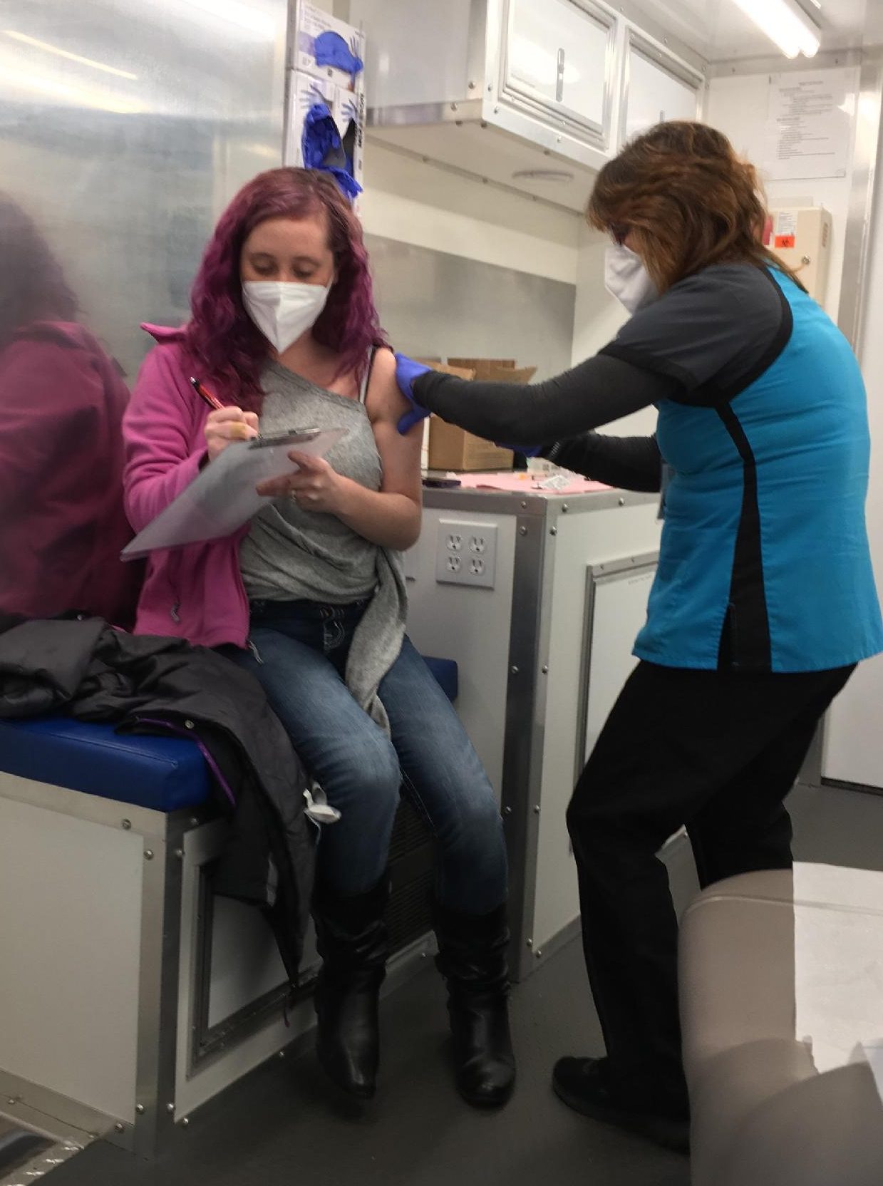 Photo of Julie Skaggs RN administering a flu shot inside the Mobile Health Unit.